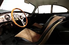 the interior of an old fashioned car with leather seats and steering wheel, in front of a large window