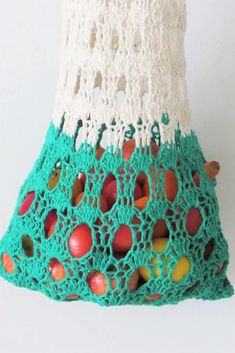 a crocheted bag with apples in it on a white surface and green trim