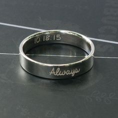 a silver ring with the word always engraved on it's side, sitting on a black surface