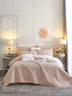 a bedroom with white walls and pink linens on the bed, along with two lamps