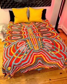 a bed covered in a colorful blanket and pillows