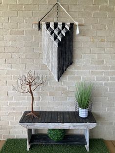 a small table with a potted plant on top and a wall hanging above it