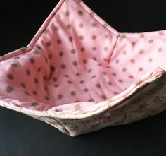 a pink and brown polka dot bag on a black surface with the bottom half open