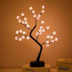 a lighted tree is sitting on top of some books