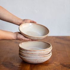 a person reaching for three bowls on top of a wooden table