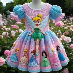 a crocheted dress with princesses on it in the middle of flowers and bushes