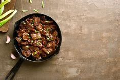 a pan filled with meat and onions on top of a table