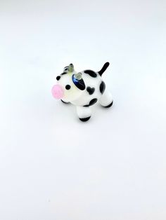 a toy cow with a pink nose on a white surface