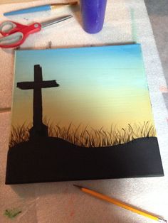 a painting of a cross on the ground with scissors and pencils next to it