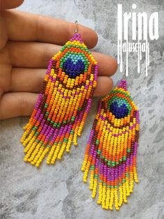 a pair of colorful beaded earrings is being held by a person's hand