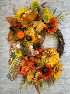 a fall wreath with sunflowers, pumpkins and other autumn flowers on a brick wall