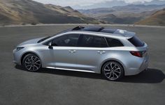 a silver car is parked in an empty parking lot with mountains in the back ground