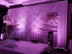 a table with flowers on it in front of a purple backdrop