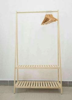 a wooden rack with clothes hanging from it's sides in front of a white wall