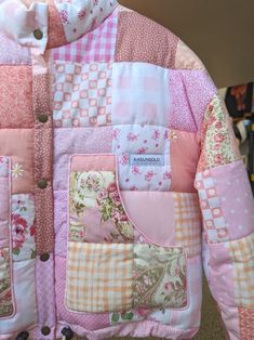 a patchwork jacket that is pink and white with flowers on the front, has buttons at the back