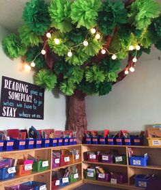 a tree with lights hanging from it's branches in a room filled with children's books