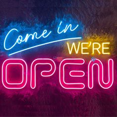 a neon sign that says come in we're open