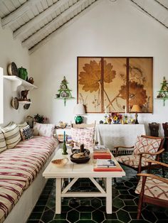 a living room filled with lots of furniture and paintings on the wall above it's coffee table