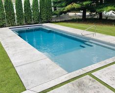 an empty swimming pool surrounded by grass and trees