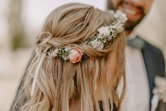 a woman with flowers in her hair standing next to a man