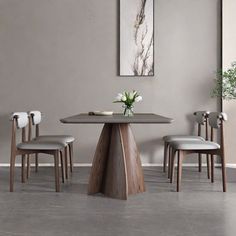 a dining room table with four chairs and a vase on the table in front of it