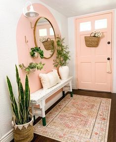 a white bench sitting in front of a pink door next to a potted plant