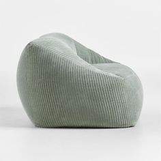 a green corded bean bag sitting on top of a white floor next to a wall