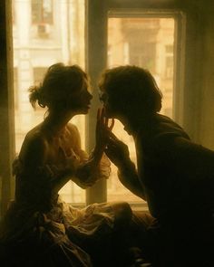 two people sitting in front of a window with their hands on each other's faces