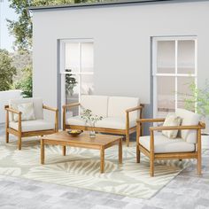 a living room filled with furniture next to a white wall and patio area covered in plants