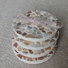 a stack of coasters made out of sea glass with a ribbon tied around them