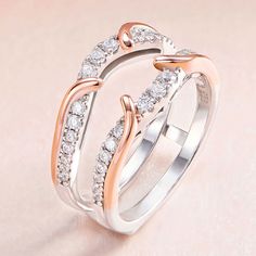 two wedding rings with diamonds on them sitting on a pink surface, one is white and the other is rose gold