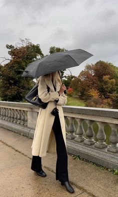 a woman standing on a bridge holding an umbrella