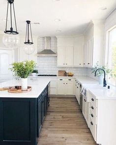 the kitchen is clean and ready for us to use it's white cabinets, black island, and wood floors