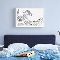 a black and white drawing of a wave on a wall above a bed with blue sheets