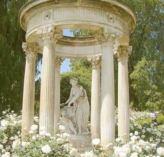 a fountain surrounded by white flowers and trees