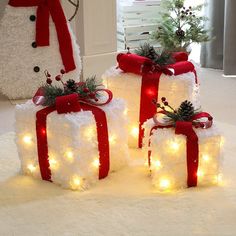 two snowmen with lights and bows on their heads