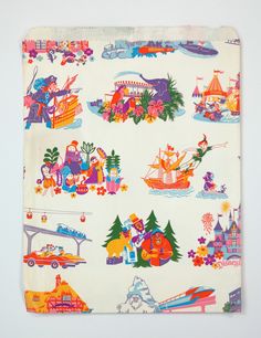 a white cloth with colorful images on it and trees, buildings, boats, and other things