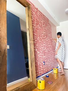 a woman is painting a wall with red and blue paint