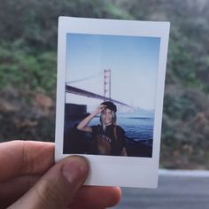 a person holding up a polaroid with the golden gate bridge in the back ground