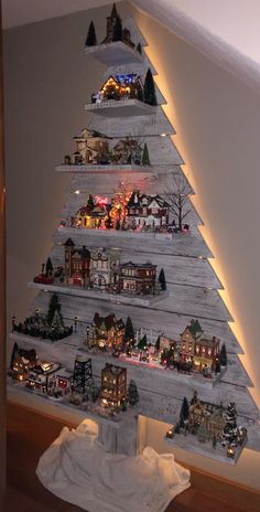 a christmas tree made out of wooden planks with lights and houses on the top
