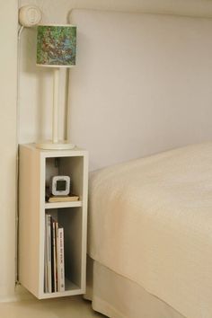 a small white shelf next to a bed