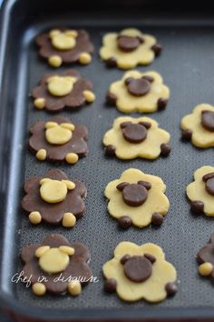 some cookies are shaped like teddy bears on a cookie sheet with chocolate and yellow icing