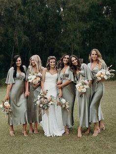 a group of women standing next to each other wearing dresses and holding bouquets in their hands