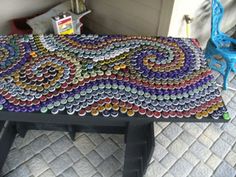 a table made out of bottle caps with a blue chair in the backgroud