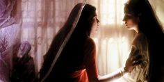 two women standing next to each other in front of a window covered with sheer curtains