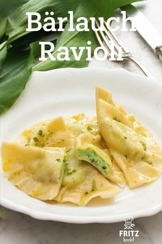 a white plate topped with ravioli next to a fork and green leafy plant