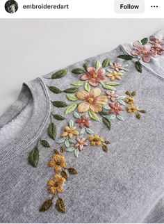 an embroidered sweater with flowers on it is shown in the middle of a t - shirt