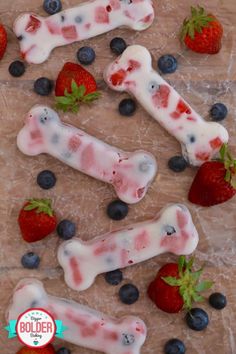 strawberries and blueberries are arranged in the shape of bone shaped dog bones with white icing