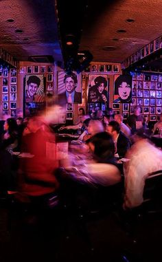 a group of people sitting at tables in a room with pictures on the walls and posters behind them