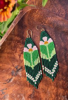 green and white beaded earrings with flowers in the background